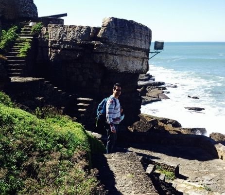 Hiker going down the steps in the cliff to the rocky beach at sea level.