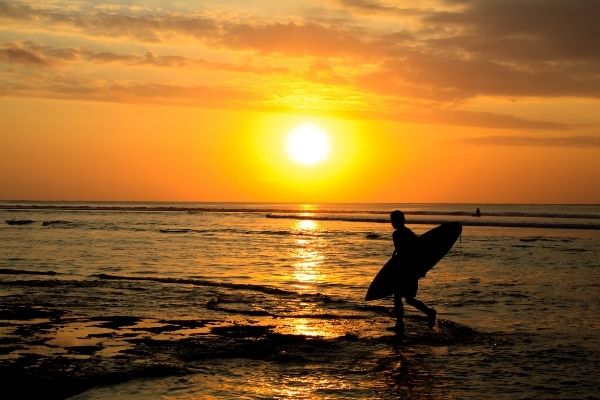Surfer at sunset. One of the best time to be at Praia de Ribeira D'Ilhas