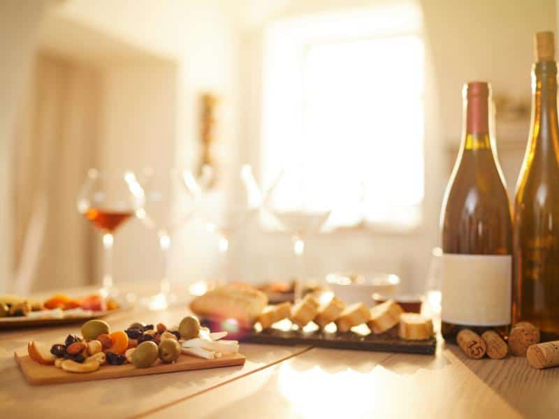 Excellent tapas board next to a few bottles of wine and glasses of wine.