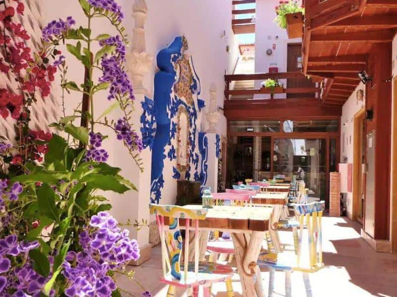 Covered patio with eating area and coloured flowers going up the walls at Villa Ana Margarida boutique hotel Ericeira.