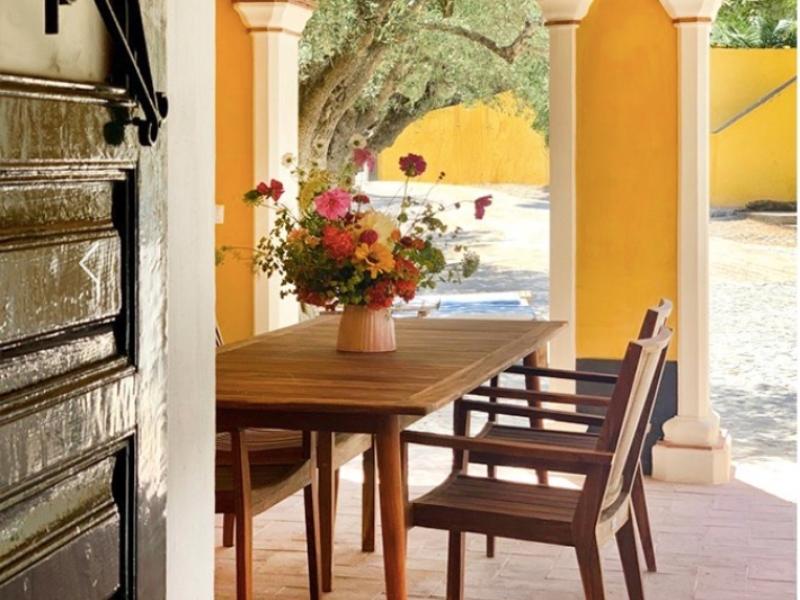 A table and chair with wild flowers in a vase in the outdoor area at Quinta da Santana boutique hotel near Ericeira.