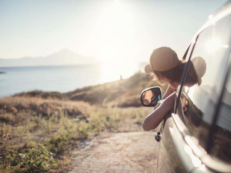 Woman driving a car along the coast from Lisbon to Porto.