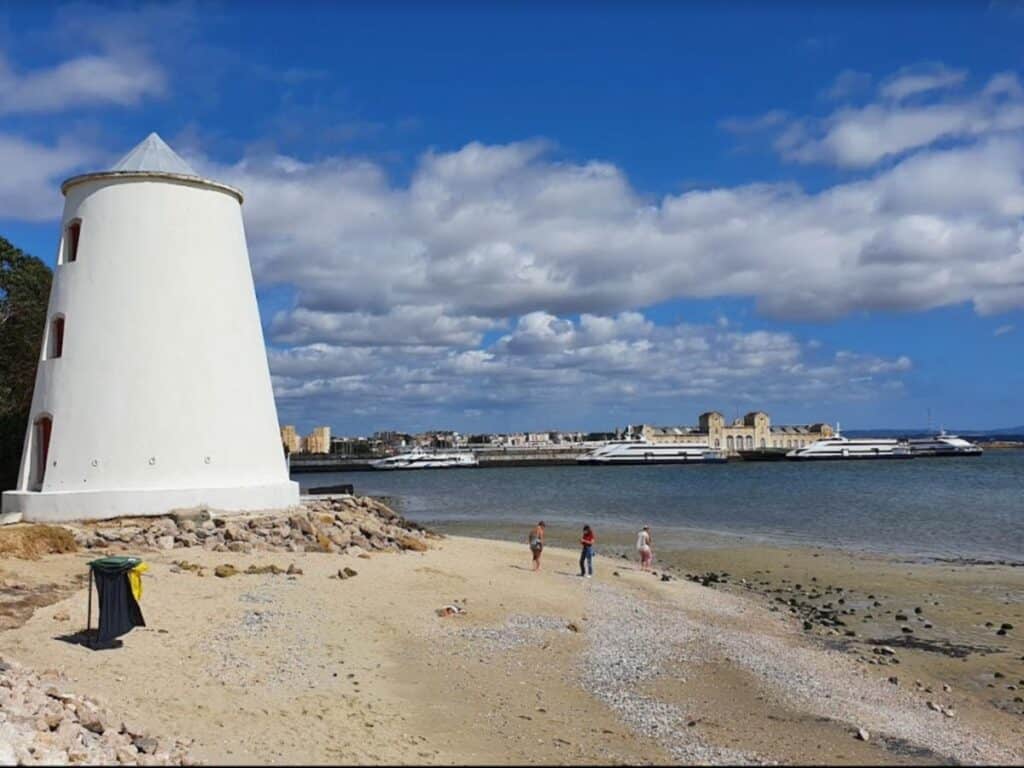 The beautiful windmill at LIsbon's nicest river beach. How far is Lisbon from the beach? Praia Fluvial de Alburrica is a 20 minute ferry ride from Lisbon's center.