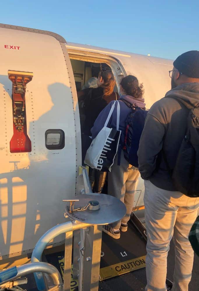 People waiting to get on a plane from the stairs up to the plane door. Lisbon Airport security wait time can be excessive so make sure to pack properly.