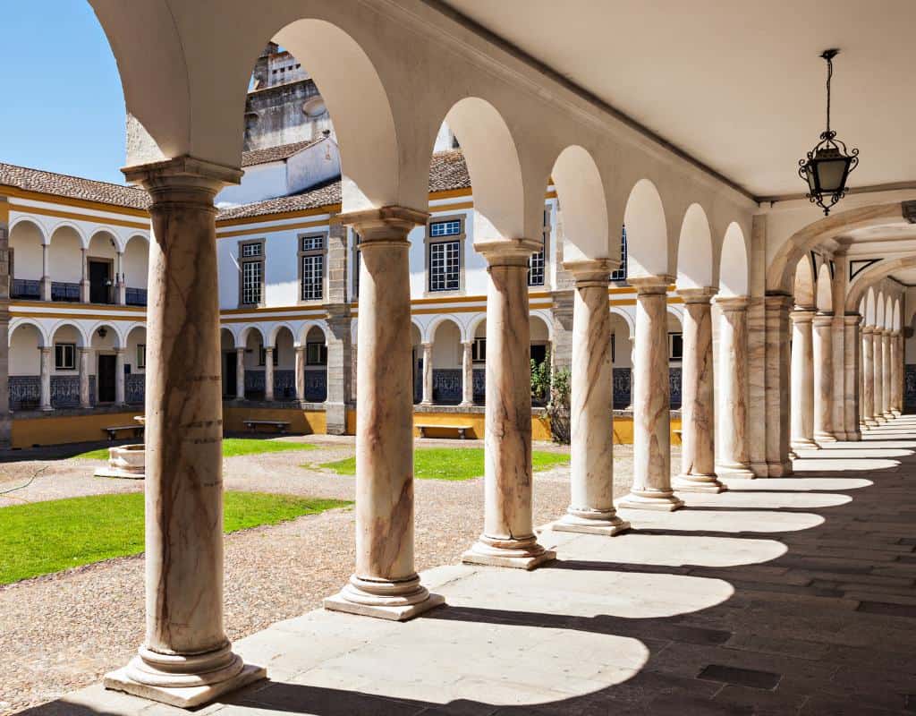 A view of Evora University's main entrance as seen from under the marble arches in its main courtyard.