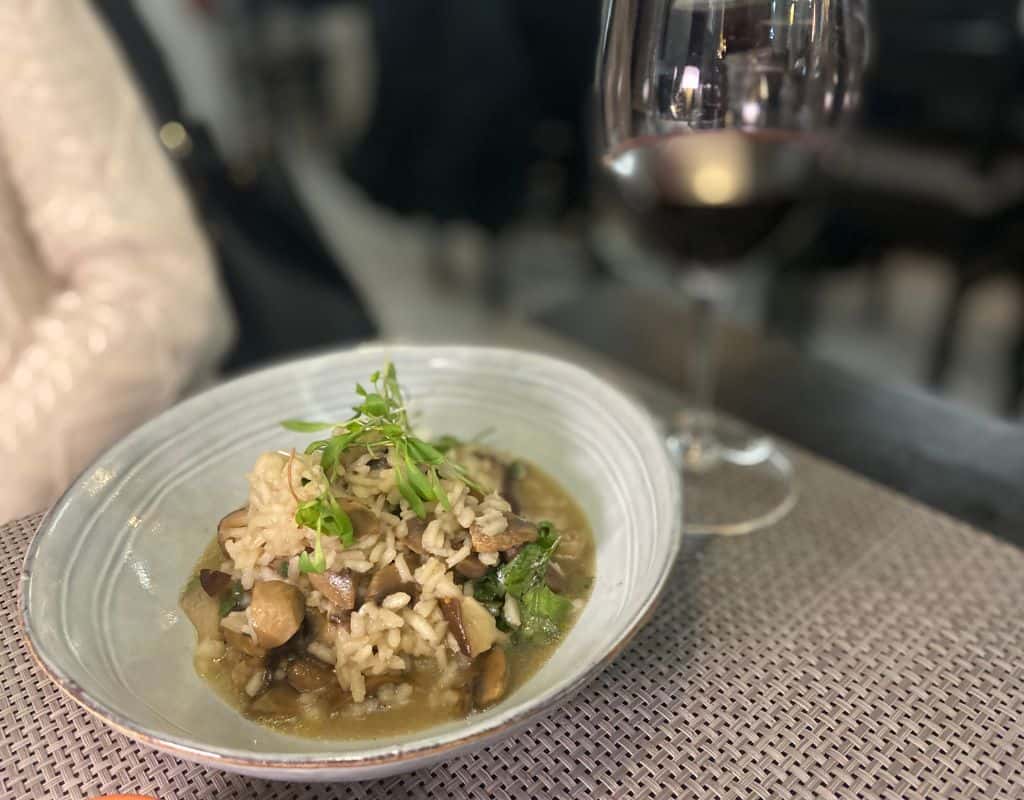 Mushroom risoto and a glass of wine on the table for dinner. What to do in Evora Portugal? Eat I say! This dish is a very popular since they are picked by the locals in the spring.