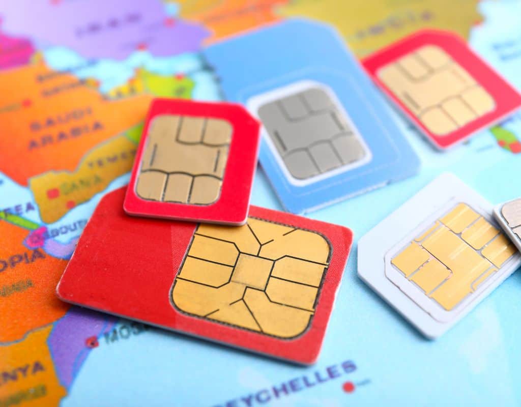 Multiple SIM cards are placed over a world map, symbolizing international travel and mobile service options, including the availability of a Portugal SIM Card for travelers.