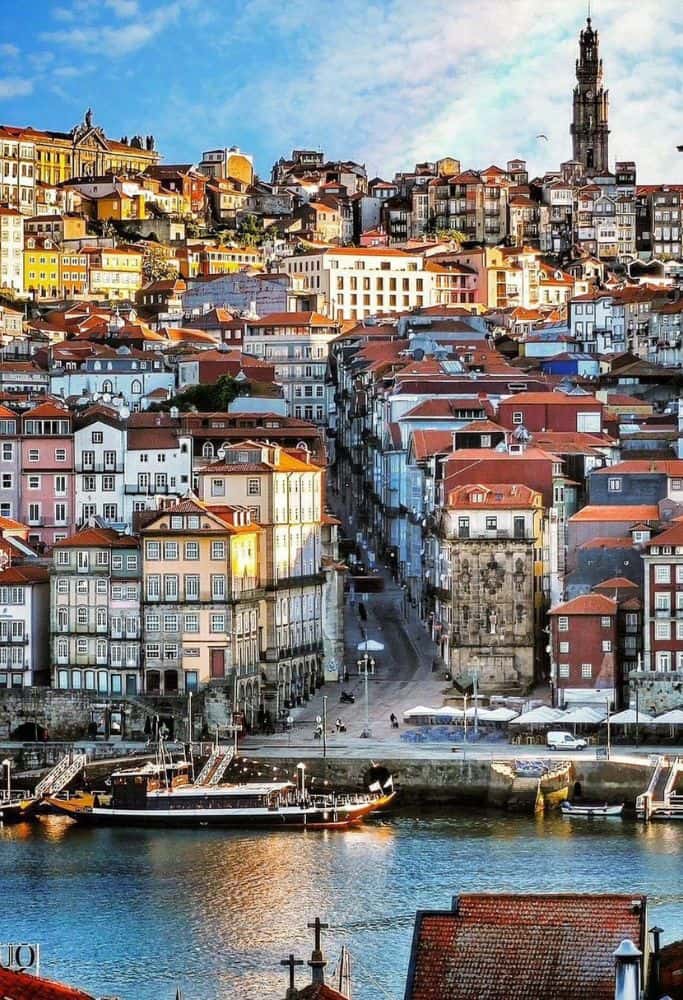 A scenic view of Porto with brightly colored buildings set along the riverbank. Interesting facts about Portugal: Porto is known for its rich history and beautiful landscapes, showcasing traditional architecture.